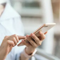 Dłoń trzyma telefon, szukając instrukcji, jak wyłączyć tryb awaryjny w telefonie.