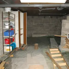 Källare med **mura lecablock**, hyllor med förvaring, rör och en uppblåsbar båt.
