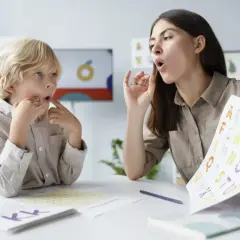 Logopeda pokazuje dziecku litery alfabetu, ćwicząc wymowę.