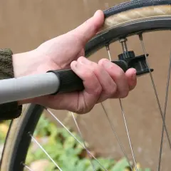 Ręka trzyma pompkę rowerową, gotową do sprawdzenia ciśnienia w oponach.