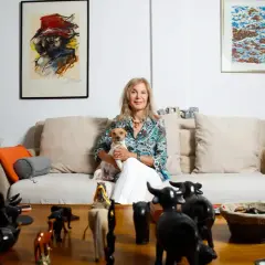 Pilar Eyre, sentada en un sofá con su perro, rodeada de arte y figuras de animales. Un vistazo a su mundo para el blog.