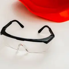 Okulary ochronne z certyfikatem ansi z87.1 i czerwony kask na białym tle.