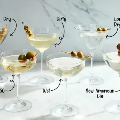 Różne rodzaje wódki z martini, od "Dry" po "Dirty", z oliwkami i etykietami wskazującymi na składniki.