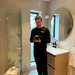Man med surfplatta i ett modernt badrum, redo för renovering badrum.