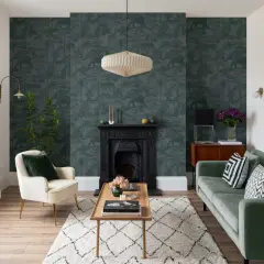 Un salotto con una **parete d'accento** a tema giungla, un camino nero, un divano verde e una poltrona color crema.