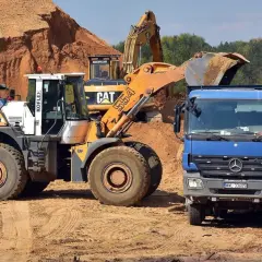 Koparki i ładowarki pracują na budowie, przygotowując teren. Operatorzy posiadają odpowiednie klasy uprawnień na koparki, by sprawnie wykonywać swoje zadania.