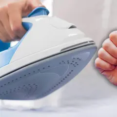 Mano sujetando una plancha blanca y azul, con un pulgar hacia arriba. Aprende como limpiar el suelo de la plancha para un planchado perfecto.