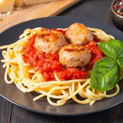 Spaghetti con tres jugosas polpette en salsa de tomate, decorado con albahaca fresca. Un plato clásico y delicioso.