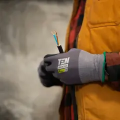 Elektryk w rękawicach ochronnych trzyma kabel elektryczny.