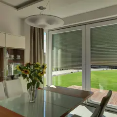 Elegancka jadalnia z widokiem na ogród. Widoczne cofnięte nadproże do rolet, nowoczesna witryna i stół ze słonecznikami.