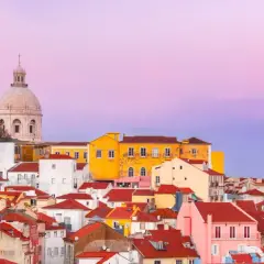 Tejado rojo y cúpula blanca bajo un cielo rosado. Un paisaje urbano que evoca las mejores experiencias en Lisboa.