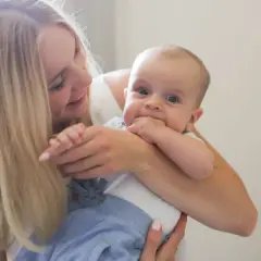 Uśmiechnięta mama tuli dziecko. To piękny widok, jakby właśnie otrzymała becikowe dla kogoś tak cudownego.