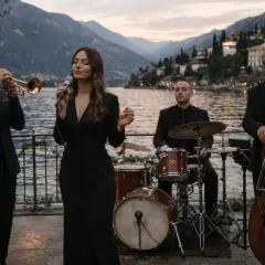Band jazz con cantante, trombettista, batterista e contrabbassista suona musica swing per un matrimonio con vista lago.