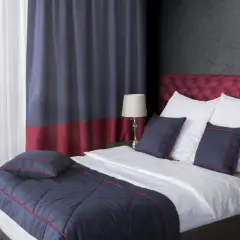 Eleganckie łóżko z pikowanym zagłówkiem, białą pościelą i granatowymi poduszkami. Pokazuje, jak pościelić łóżko w stylu hotelowym.