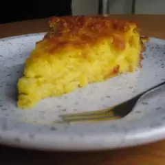 Una rebanada de torta de maiz dorada y esponjosa en un plato, lista para ser disfrutada con un tenedor.