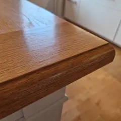 Närbild på ett oljat ekbord med vacker ådring. Bordsskivan har en rundad kant och vilar på en vit bordsstomme.