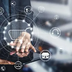 Biznesmen korzysta z tabletu, na którym wyświetla się grafika przedstawiająca koszyk zakupowy i ikony związane z e-commerce, takie jak drp ii.