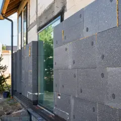 Moderne fassadengestaltung: Dämmplatten aus Polystyrol werden an einer Hauswand angebracht. Ein Fenster ist bereits eingesetzt.