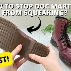 Hands hold a burgundy Doc Marten boot, showing its sole. A second boot sits nearby. Learn why are my boots squeaking when I walk and how to fix it FAST!