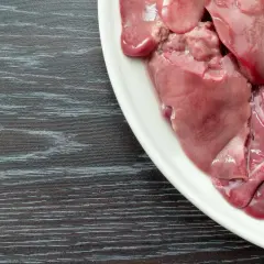 Piatto bianco con durelli di pollo crudi, pronti per essere cucinati.