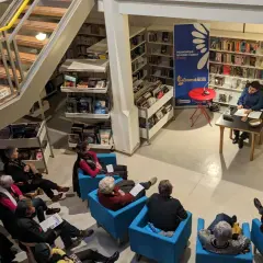 Une bibliothécaire présente un livre à un public assis. Une gestion des actifs numériques efficace permet de retrouver facilement ce type de contenu.