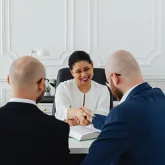 Uśmiechnięta kobieta w białej bluzce ściska dłoń mężczyzny w garniturze. Rozmowa o tym, kiedy aneks do umowy jest nieważny.