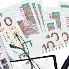 Złotówki, kalkulator, okulary i długopis. Niespłacanie pożyczki może prowadzić do takich rachunków.