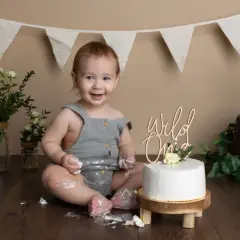 Glad baby firar 1-årsfotografering med tårta. Tips för en lyckad fotografering: lekfull miljö, tårta och glada barn.