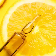 Fetta di limone brillante con fiala di siero alla vitamina C, un concentrato di freschezza e benessere.
