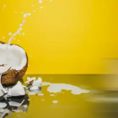 Éclaboussures de lait de coco sur fond jaune vif, révélant la texture crémeuse du lait de coco.