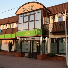 Budynek banku z zielonym neonem i napisem "BANK". W tle widać parking, co może sugerować upadłe banki w Polsce.