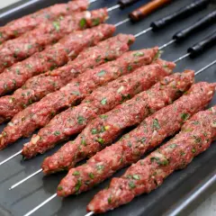 Rå irakisk kebab på spett, redo för grillen. Kryddad färs med lök och örter.