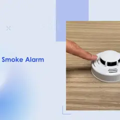 Ein Finger drückt auf einen weißen Rauchmelder, um einen Fehlalarm zu beenden.