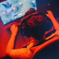 Gracz w słuchawkach przed monitorem, przygotowuje się do gry. Chcesz wiedzieć, jak zarejestrować się na Steamie?