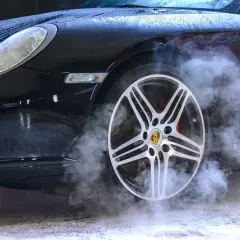 Czarny Porsche z dymem unoszącym się z koła. Sprawdź ozonowanie samochodu cennik, by odświeżyć wnętrze.