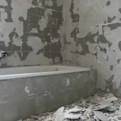 Łazienka w trakcie remontu, z odsłoniętymi ścianami i gruzem.
