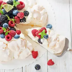 Beza pavlova która zawsze wychodzi, udekorowana świeżymi malinami, borówkami, jeżynami i plasterkami limonki.