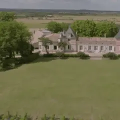 Un magnifique château bordelais, typique de la route des châteaux du Médoc, se dresse au milieu de vignes et d'arbres verdoyants.