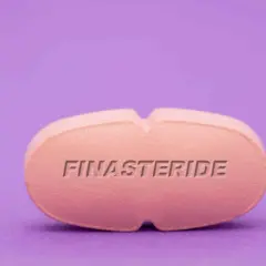 Różowa tabletka z napisem FINASTERIDE na fioletowym tle.