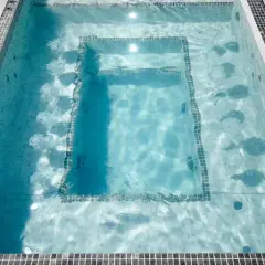Un jacuzzi moderne avec des jets d'eau, entouré de carrelage et de dalles grises. Le poids d'un jacuzzi rempli d'eau est considérable.