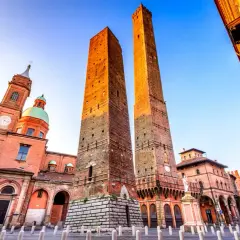 Le Due Torri svettano maestose nella piazza Maggiore di Bologna, con la Basilica di San Petronio sullo sfondo.