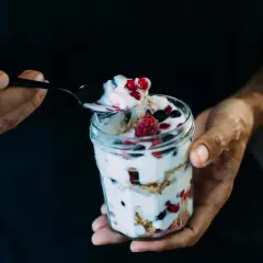 Ein Glas mit Magerquark, Beeren und Knuspermüsli. Perfekt für gesunde Magerquark Rezepte.