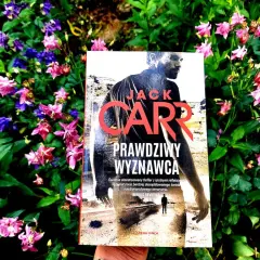 Prawdziwy Wyznawca" Jacka Carra, thriller w otoczeniu kwitnących kwiatów.