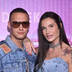 Mateusz Świerczyński z Love Island w dżinsowej kurtce i jego partnerka z naszyjnikiem na tle różowej ściany.