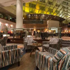 Przytulne fotele w paski w lobby hotelu Hyatt Warszawa, pod przeszklonym dachem.