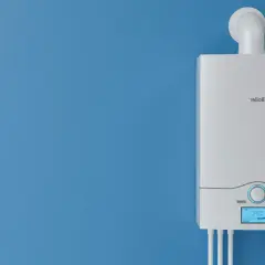 Nowy, biały piec gazowy na niebieskiej ścianie. Dowiedz się, jak wyłączyć piec gazowy na lato, aby zaoszczędzić energię.