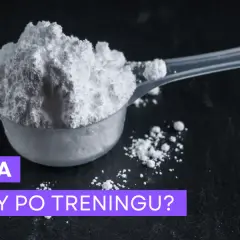 Miarka z białym proszkiem kreatyny na ciemnym tle.