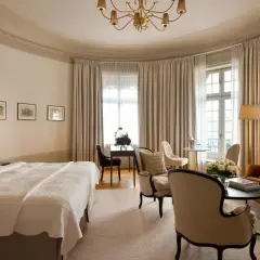 Ett elegant rum på Clarion Hotel Östermalm med en stor säng, soffa, skrivbord och vackra gardiner.