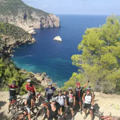 Grupo de ciclistas disfrutando de una ruta de ibiza en bicicleta con vistas espectaculares al mar Mediterráneo.