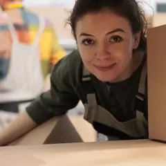 Donna sorridente con scatole, pronta per organizzare un trasloco senza stress.